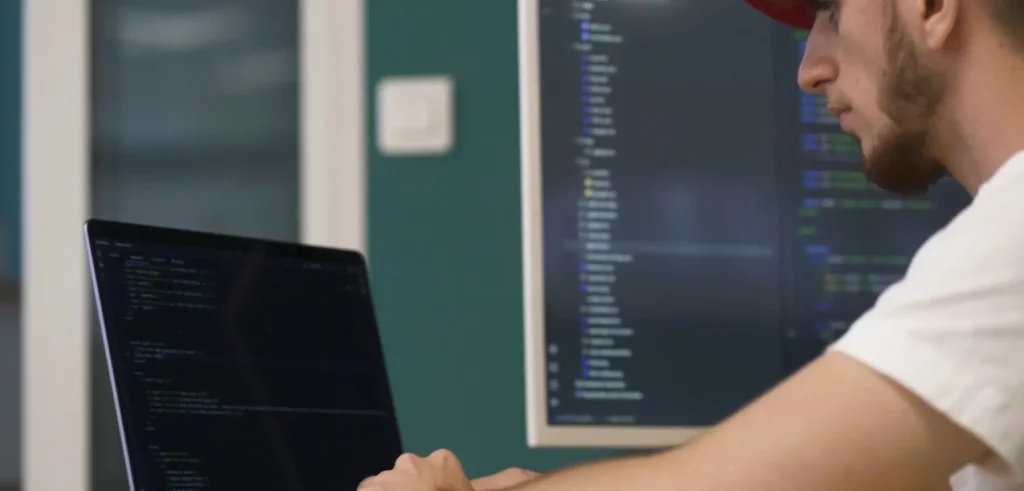 Homme derrière un ordinateur en train de coder pour des logiciels CFAO